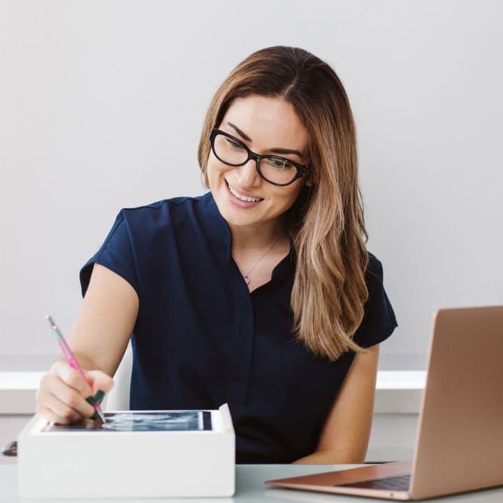 Zahntechnikerin am Laptop mit Notizblock