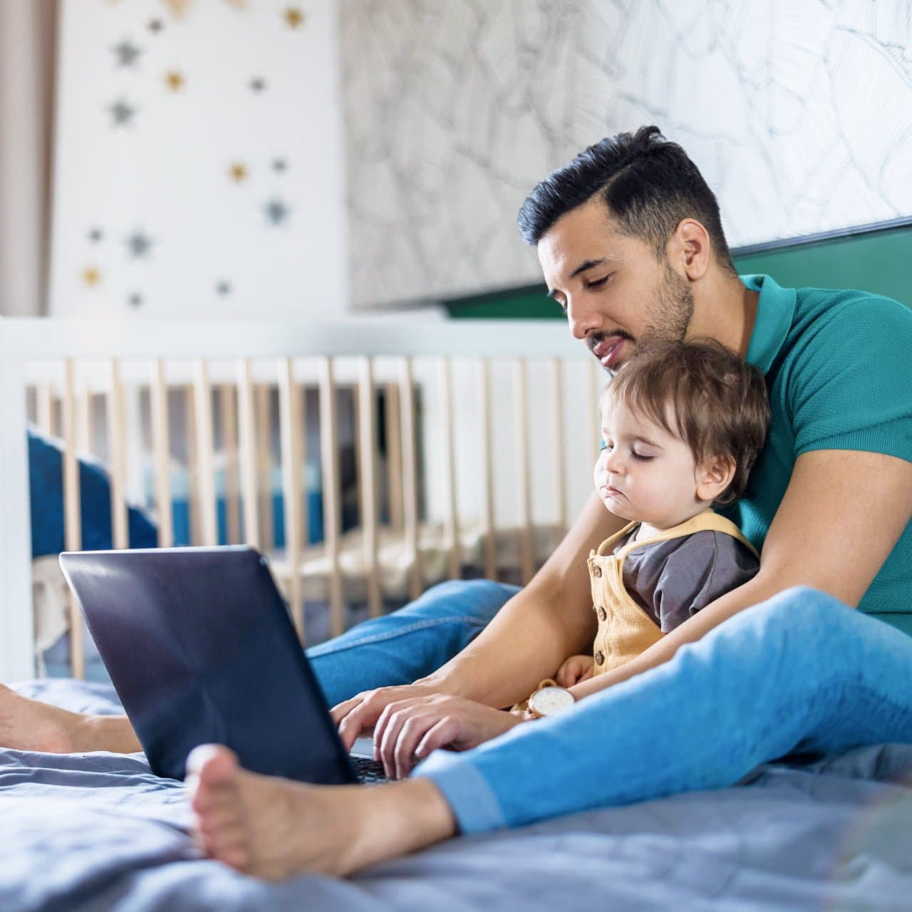 Zahntechniker mit Kind auf dem Bett am Laptop